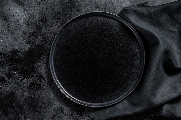 Runde schwarze Platte auf strukturiertem schwarzem Hintergrund