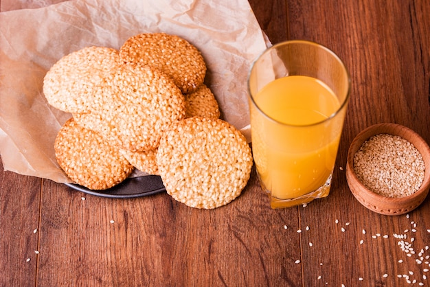 Runde Sesamplätzchen mit Milch und Saft auf dem Tisch.