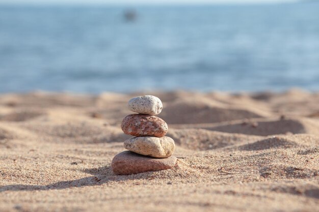 Runde Steine liegen an einem sonnigen Sommertag in einer Säule am Meeresufer übereinander.
