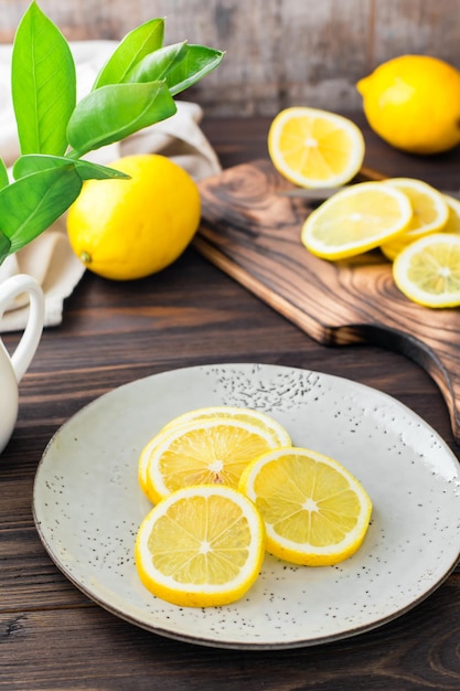 Runde Stücke reifer Zitronen auf einem Teller und auf einem Holzschneidebrett auf dem Tisch. Bio-Ernährung, Vitaminquelle. Vertikale Ansicht