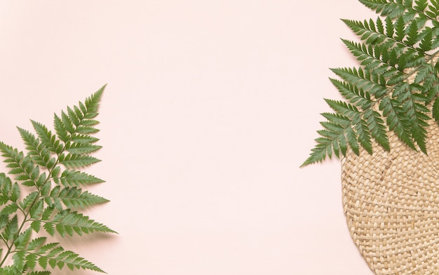 Foto runder korbständer und palmblätter auf rosa wand. flatlay-öko-stil-konzept mit textplatz