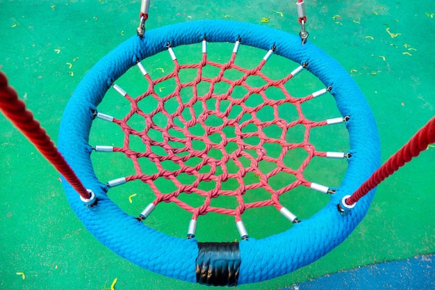 Runder Schaukelsitz aus Mesh auf dem Spielplatz Leeres blaues Seilnest zum Schaukeln in der Nähe