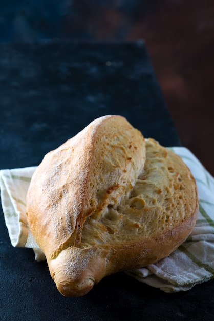 Rundes frisch gebackenes rundes Brot des rustikalen Roggens mit den Weizenähren und Serviette auf Dunkelheit