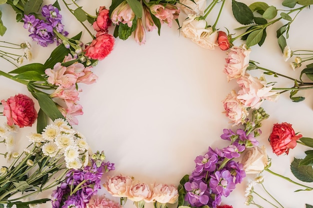 Rundes Rahmenkranzmuster mit Rosen, rosafarbenen Blütenknospen, Ästen und Blättern, die auf weißem Hintergrund isoliert sind Flache Ansicht von oben Ästhetische florale Vorlage mit Leerzeichen