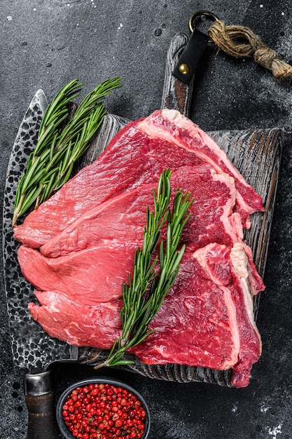 Rundes Steak mit rohem frischem Rindfleisch mit Kräutern und Gewürzen. Schwarzer Hintergrund. Draufsicht.