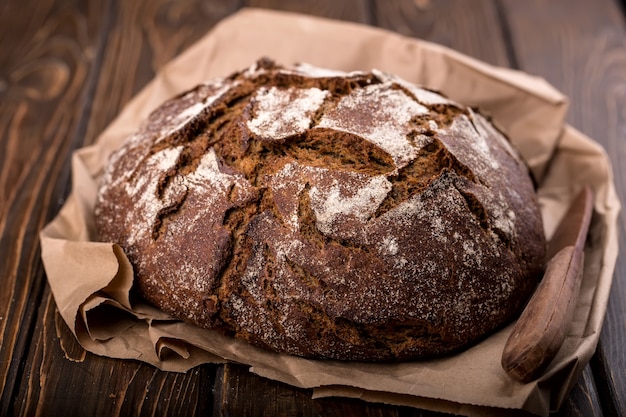 Foto rundes warmes frisches brot und auf altem holztisch und auf papier, waagerecht