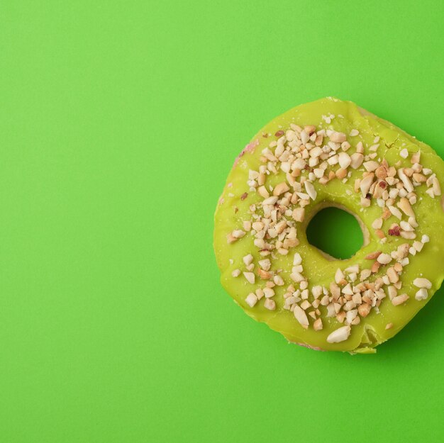 Rundgebackener Donut mit grüner Pistazienglasur, bestreut mit zerdrückten Nüssen