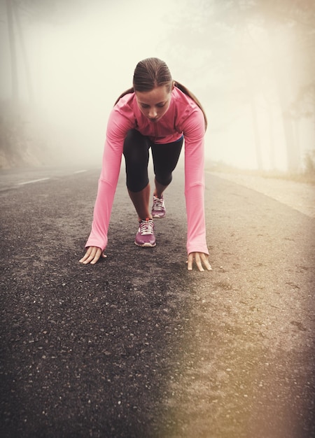 Runner start y mujer en el camino al aire libre en el parque forestal o el bosque para el ejercicio en invierno Niebla matinal y persona con desafío de fitness o prepararse para el entrenamiento en la carretera en el campo con la naturaleza