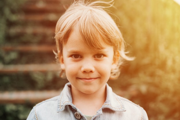 Rusia 06292021 retrato de la cara de un lindo feliz sonriente pequeño niño de cinco años de edad rubio largo caucásico preescolar o educador en el hogar niño en la naturaleza cerca de la infancia cuidadosa de los niños bengala