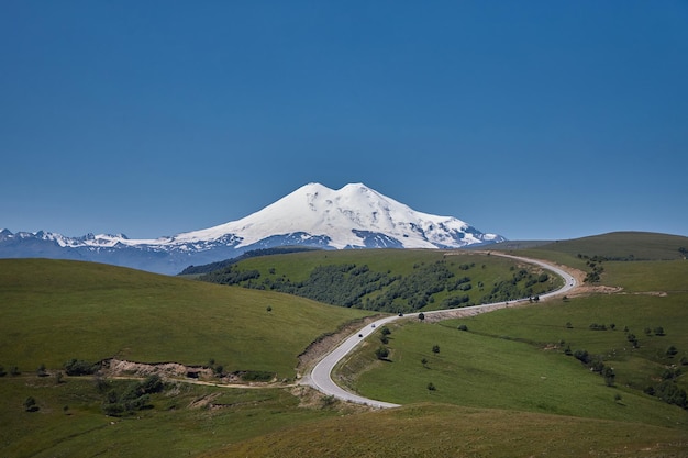 Rusia Cáucaso Monte Elbrus torres majestuosamente adornadas en nieve y hielo prístino Paisaje alpino cuenta con vistas panorámicas de crestas escarpadas valles serenos y glaciares helados bajo el vasto cielo azul