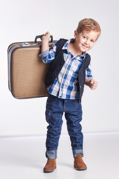 Rusia Ekaterinburg - 1 de abril de 2016: El niño pequeño que se coloca con una maleta en mano, se va de vacaciones.