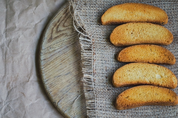 Rusk pão branco sobre tela e papel de embrulho vintage, tonificado e desbotado