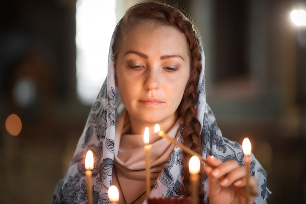 Russa linda mulher caucasiana com cabelo vermelho e um lenço na cabeça é na Igreja Ortodoxa