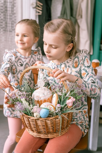 Rússia Moscou 04092022 feliz feriado de páscoa na temporada de primavera família e crianças pequenas irmãs seguram cesta com ovos pintados e bolos assados de páscoa decoração festiva para casa comida tradicional