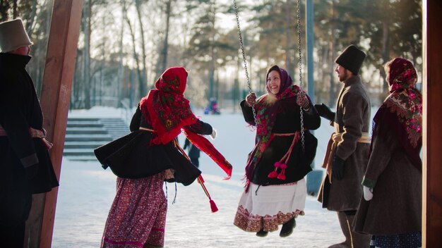 Russische Folklore Russische Frau schwingt und alle lachen an einem sonnigen Tag