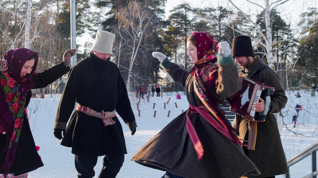 Russische Folkloreleute in Filzstiefeln tanzen im Winter im Freien im Park