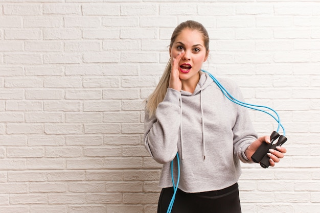 Russische Frau der jungen Fitness, die ein Springseil gegen eine Ziegelwand hält