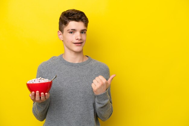 Russische frau des teenagers, die einen gelben hintergrund hält, der auf die seite zeigt, um ein produkt zu präsentieren