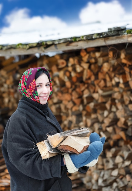 Russische Frau in Winterkleidung mit Brennholz