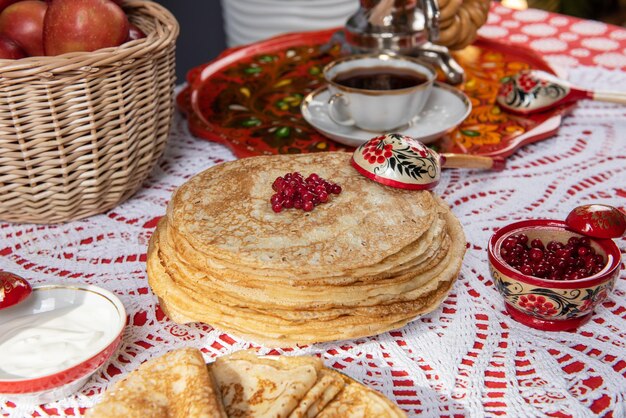 Russische Pfannkuchen-Blini mit Beeren und Sauerrahm auf dem Tisch Shrovetide Maslenitsa Festival concep