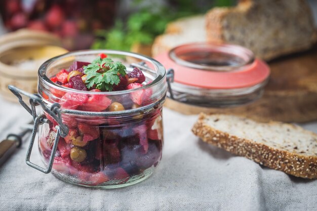 Russische Rote-Bete-Salat-Vinaigrette im Glas mit Roggenbrot, rustikaler Hintergrund