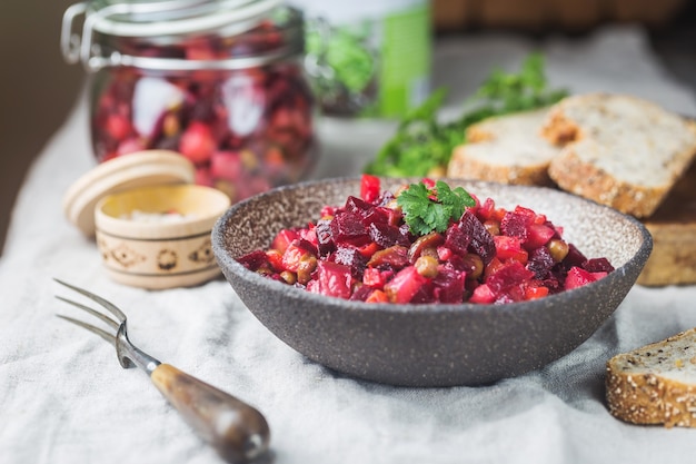 Russische Rote-Bete-Salat-Vinaigrette in einer Schüssel mit Roggenbrot, rustikaler Hintergrund