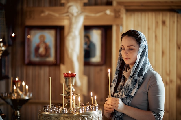 Russische schöne kaukasische Frau mit dem roten Haar und einem Schal auf ihrem Kopf ist in der orthodoxen Kirche