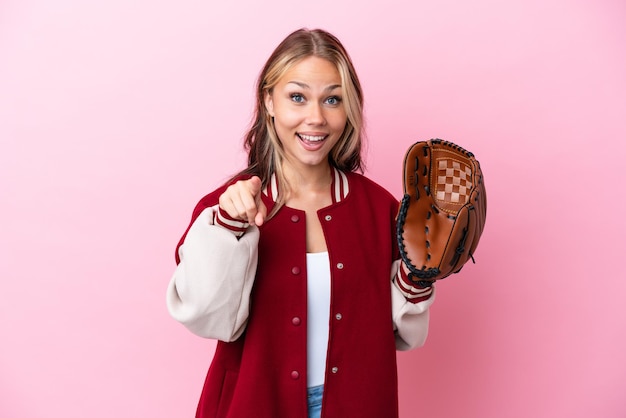 Russische Spielerin mit Baseballhandschuh isoliert auf rosa Hintergrund überrascht und zeigt nach vorne