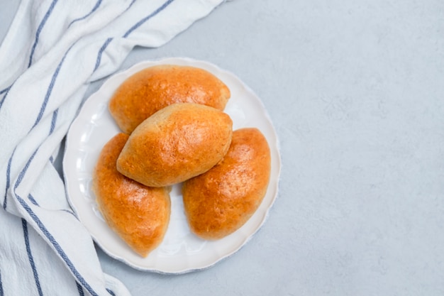 Russische traditionelle Kuchen pirozhki (gefüllte Brötchen) auf weißem Teller