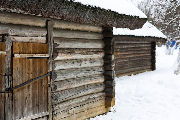 Russische Winterlandschaft Eine alte Holzhütte ein Blockhaus mit Strohdach Verlassenes russisches Dorf mit Schnee bedeckt Blockhaus mit Scheune