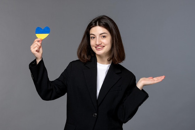 Russischer konflikt in der ukraine süße junge frau mit dunklen haaren im blazer mit ukrainischer flagge lächelnd