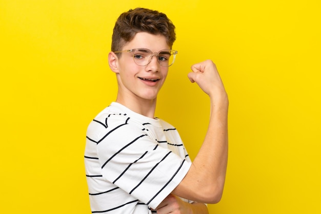 Russischer Mann des Teenagers lokalisiert auf gelbem Hintergrund mit Gläsern und feiert einen Sieg