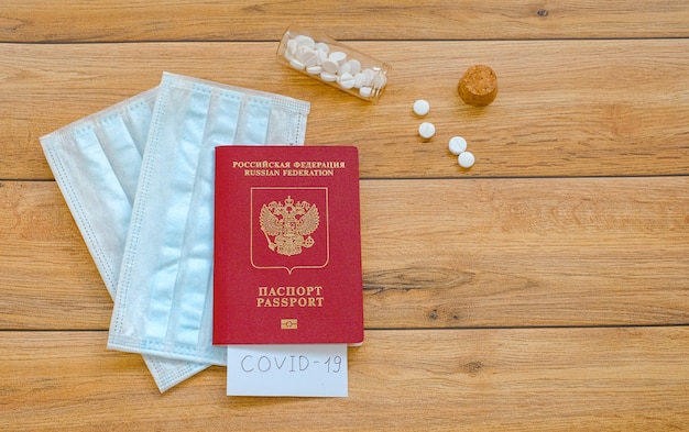 Russischer Pass mit der Aufschrift Covid-19, Schutzmasken und Tabletten