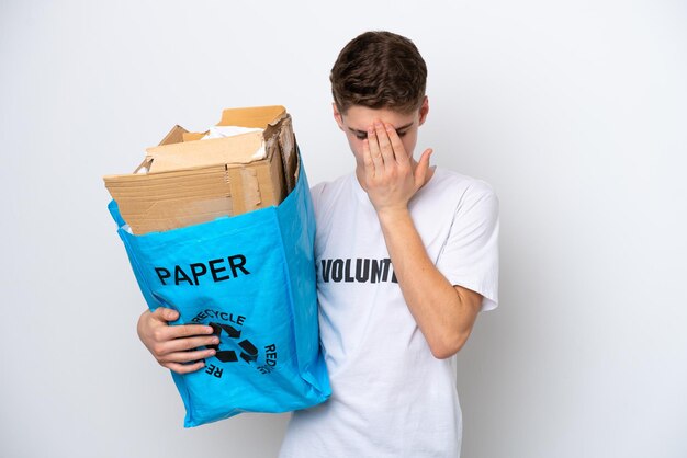 Russischer Teenager, der einen Recycling-Beutel voller Papier hält, um isoliert auf weißem Hintergrund mit müdem und krankem Ausdruck zu recyceln