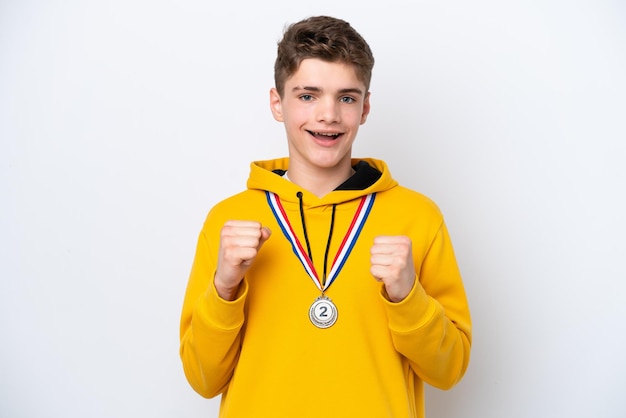 Russischer Teenager mit Medaillen isoliert auf weißem Hintergrund, der einen Sieg in Siegerposition feiert