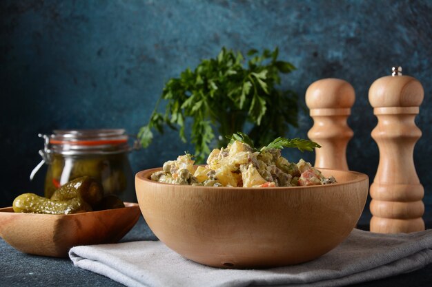 Russischer traditioneller Salat "Olivier" mit Gemüse und Fleisch und Mayonnaise. Wintersalat. Rustikaler Stil. Salat in Holzschale