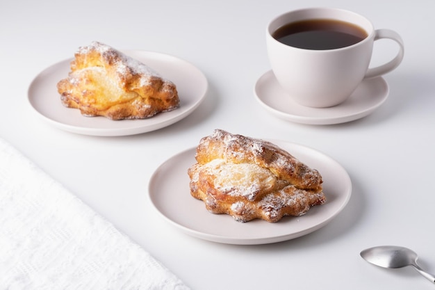 Russisches Backen mit Hüttenkäse Sochniki mit Hüttenkäse auf dem Teller und einer Tasse Kaffee