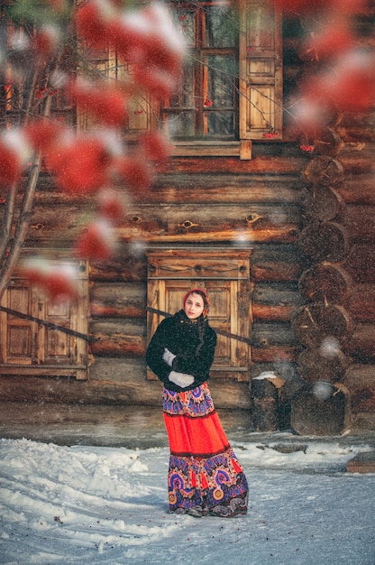 Russisches Mädchen im Winter im Dorf nahe altem Haus