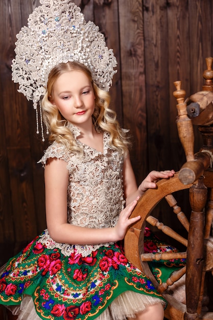 Russisches Mädchen in einem russischen Volkskleid auf hölzernem Hintergrund
