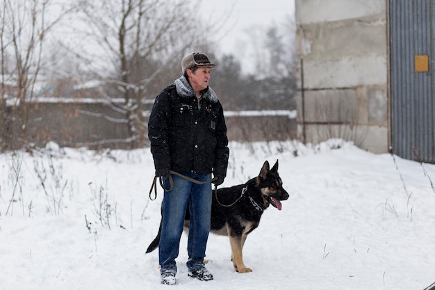 Russland Ivanovo 24. Dez. 2017 Ein älterer Mann geht mit einem Deutschen Schäferhund in der Winterredaktion spazieren