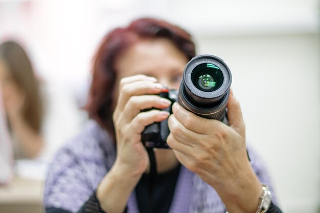 Russland Sankt Petersburg Oktober 2020 eine erwachsene Frau mit einer SLR-Kamera in den Händen in einem hellen Raum, die die Kamera studiert