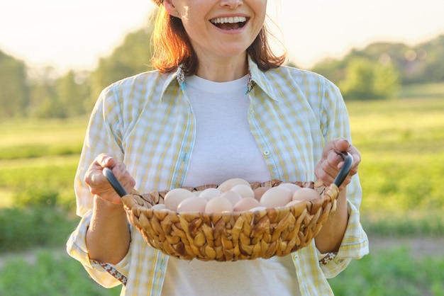 Rústico retrato de mujer madura con canasta de huevos en la pradera