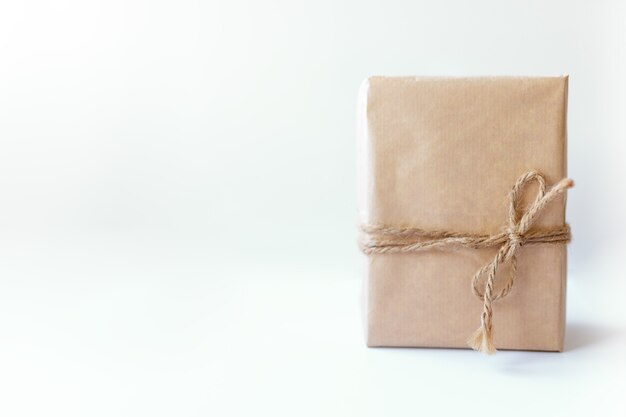 Rustikale Geschenkbox verpackt in braunem Papier, das mit Schnur mit leerem auf weißem Hintergrund mit Platz für Text gebunden ist