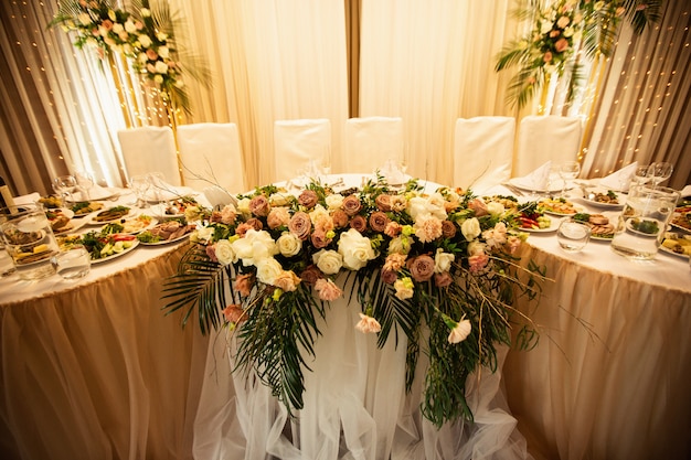 Rustikale Hochzeitsdekorationen mit Blumen und Glühlampen. Bankett-Dekor