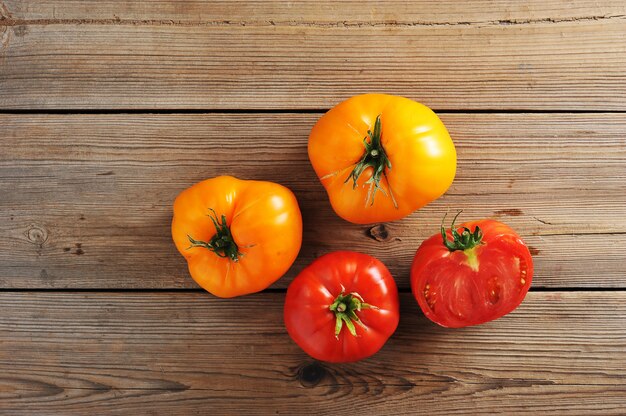 Rustikale Holzoberfläche der gelben und roten rohen reifen ganzen Tomaten