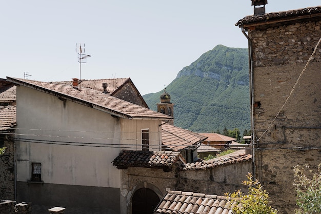 Rustikale italienische Architektur. Italienisches Dorf in den Bergen mit traditionellen Gebäuden, Holzfenstern, Blumen und blühenden Bäumen. Ästhetisches Reisekonzept für den Sommerurlaub