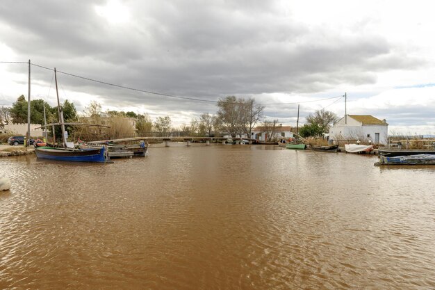 Rustikale Riverside-Szene mit verankerten Booten und bewölktem Himmel