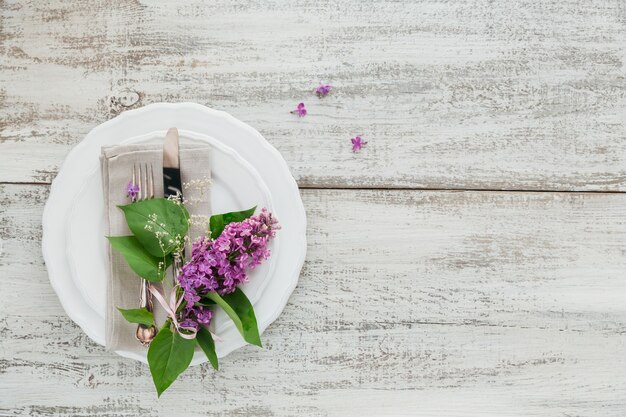 Rustikale Tischdekoration mit lila Blumen auf hellem Holztisch