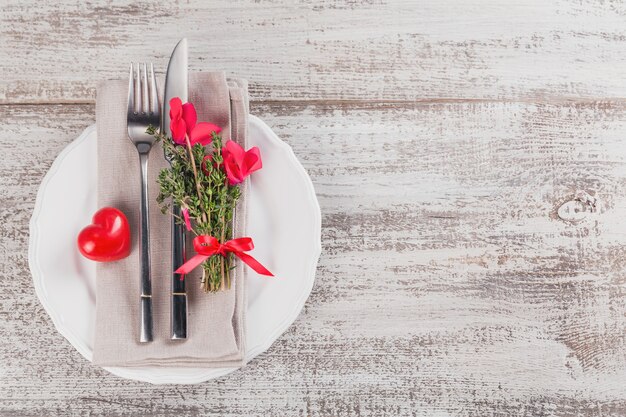 Rustikale Tischdekoration mit Thymian- und Alpenveilchenblüten und Form der Herzdekoration auf hellem Holztisch mit Copyspace