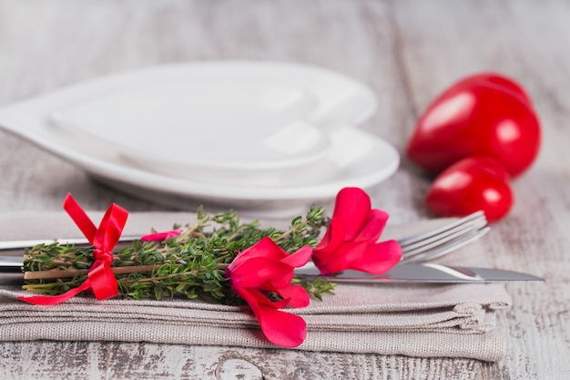 Rustikale Tischdekoration mit Thymian- und Alpenveilchenblüten und Form der Herzdekoration auf hellem Holztisch mit Copyspace